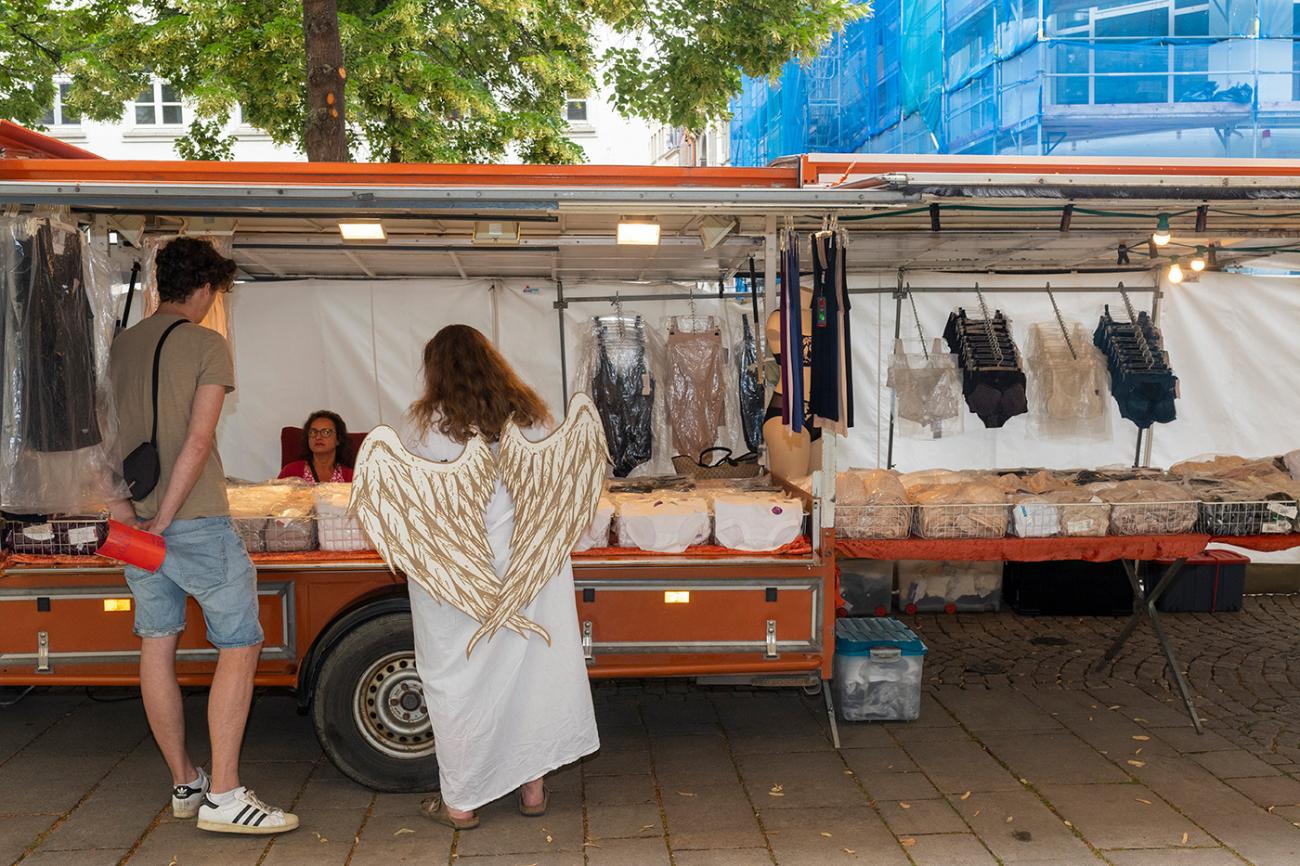 Erzengel Gabriel befragt Bürger an einem Marktstand