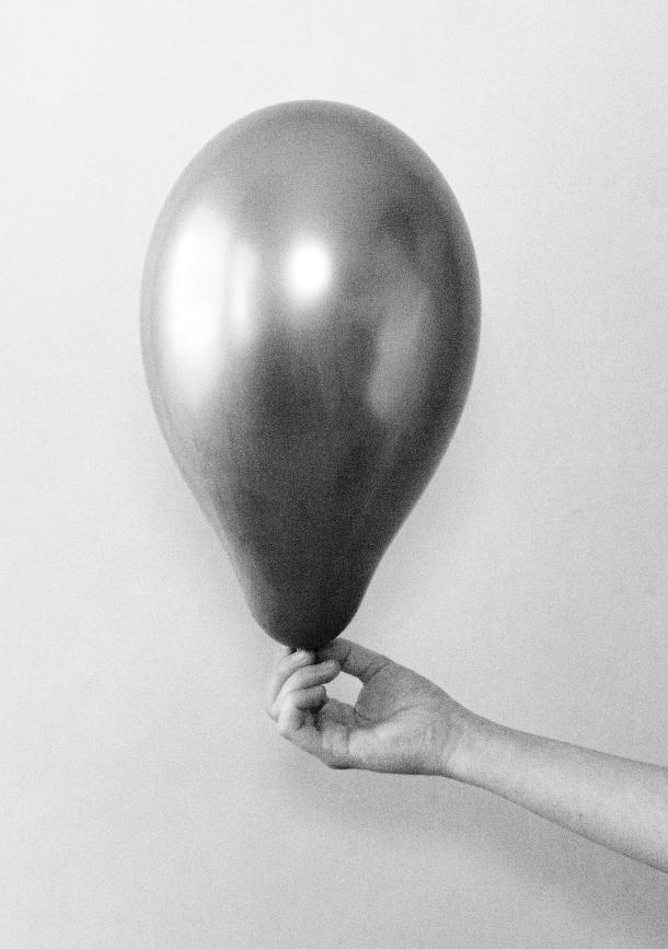 Eine Person hält einen silbernen Luftballon in einem schwarz-weiß Foto.