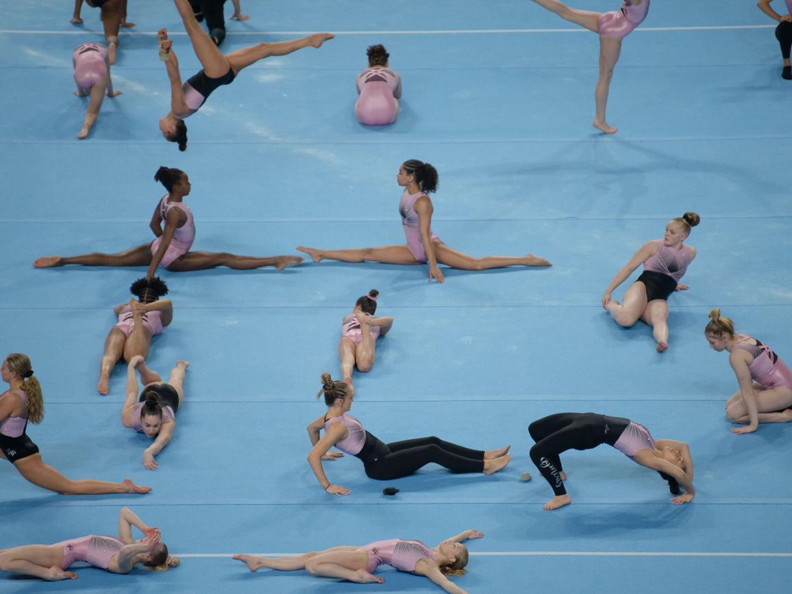Eine Gruppe von Turnerinnen führt auf einem blauen Boden ihre Übungen vor.