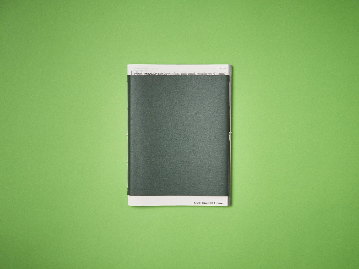 Das Bild zeigt das Cover des Buches. Das Cover ist in ein grünes Leinen gebunden. Unten links am Seitenrand steht der Titel »Seele braucht Heimat«.