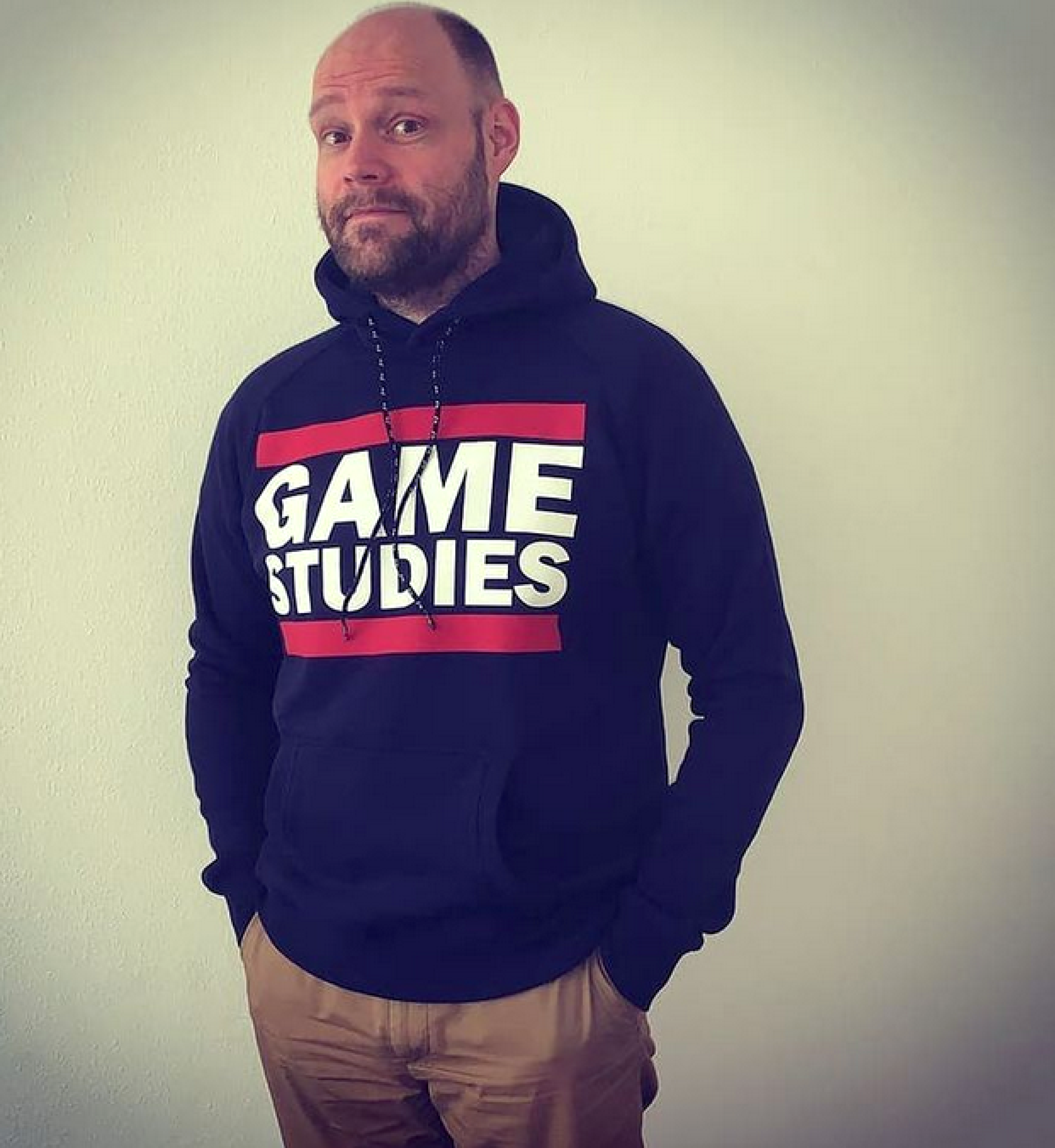 Dr. Rudolf Inderst trägt eine Hoodie mit dem Text "Game Studies" an der Vorderseite. 